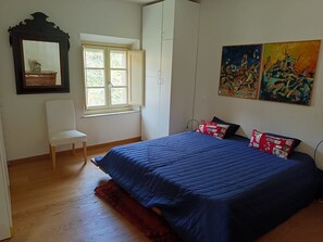 A bedroom with a bed, a chair, a window, a wardrobe, and two paintings. - Apartment 'Calci - Dal Monte Al Mare' with Mountain View, Garden and Wi-Fi (Calci)