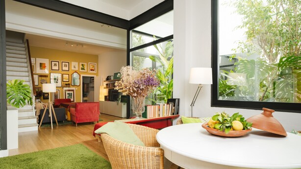 A modern interior with a dining area, wicker chairs, a red sofa, and a view of greenery outside. - Holiday Home 'Art and Relaxation in Seville' with Private Terrace, Wi-Fi & Air Conditioning (Sevilla)