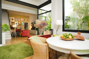 A modern interior with a dining area, wicker chairs, a red sofa, and a view of greenery outside. - Holiday Home 'Art and Relaxation in Seville' with Private Terrace, Wi-Fi & Air Conditioning (Sevilla)