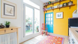 A room with a large window, a wooden desk, a colorful rug, a red chair, and a bookshelf. - Holiday Home 'Art and Relaxation in Seville' with Private Terrace, Wi-Fi & Air Conditioning (Sevilla)