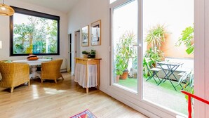 A bright room with a dining area, a window, and a view of the garden. - Holiday Home 'Art and Relaxation in Seville' with Private Terrace, Wi-Fi & Air Conditioning (Sevilla)