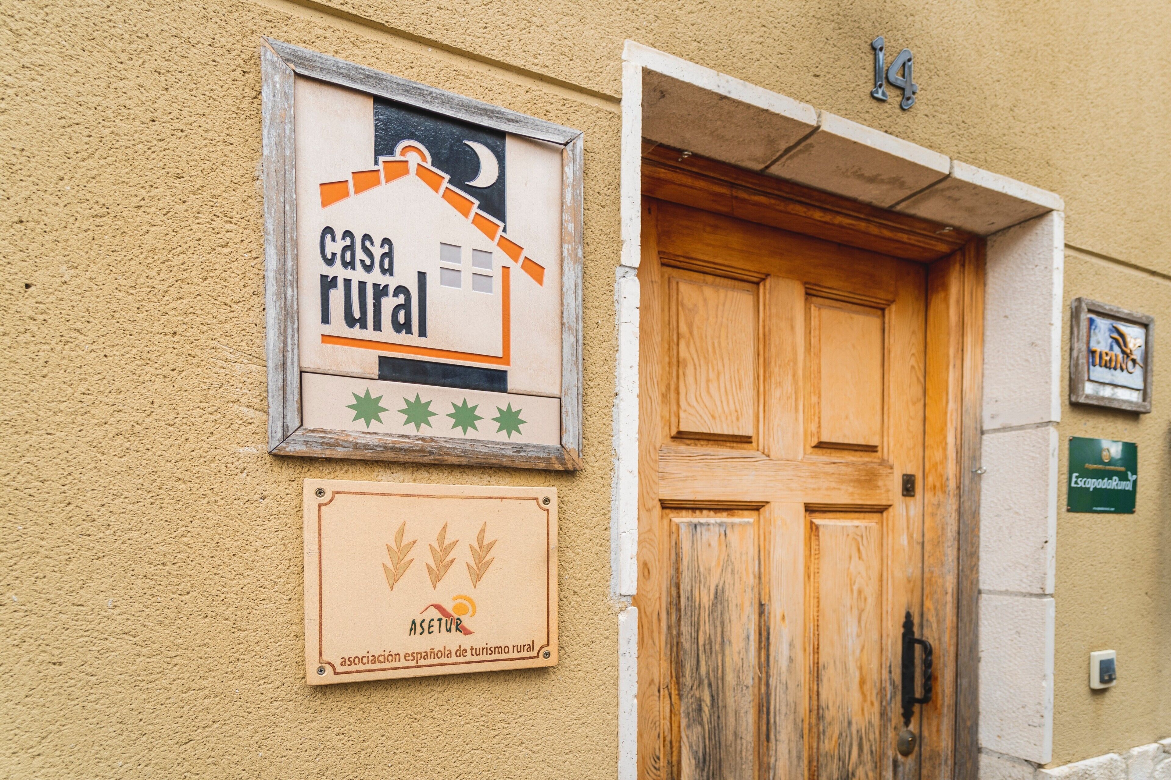 Une entrée rustique avec une porte en bois, une enseigne indiquant « casa rural » et une plaque portant le nom « Asetur ».