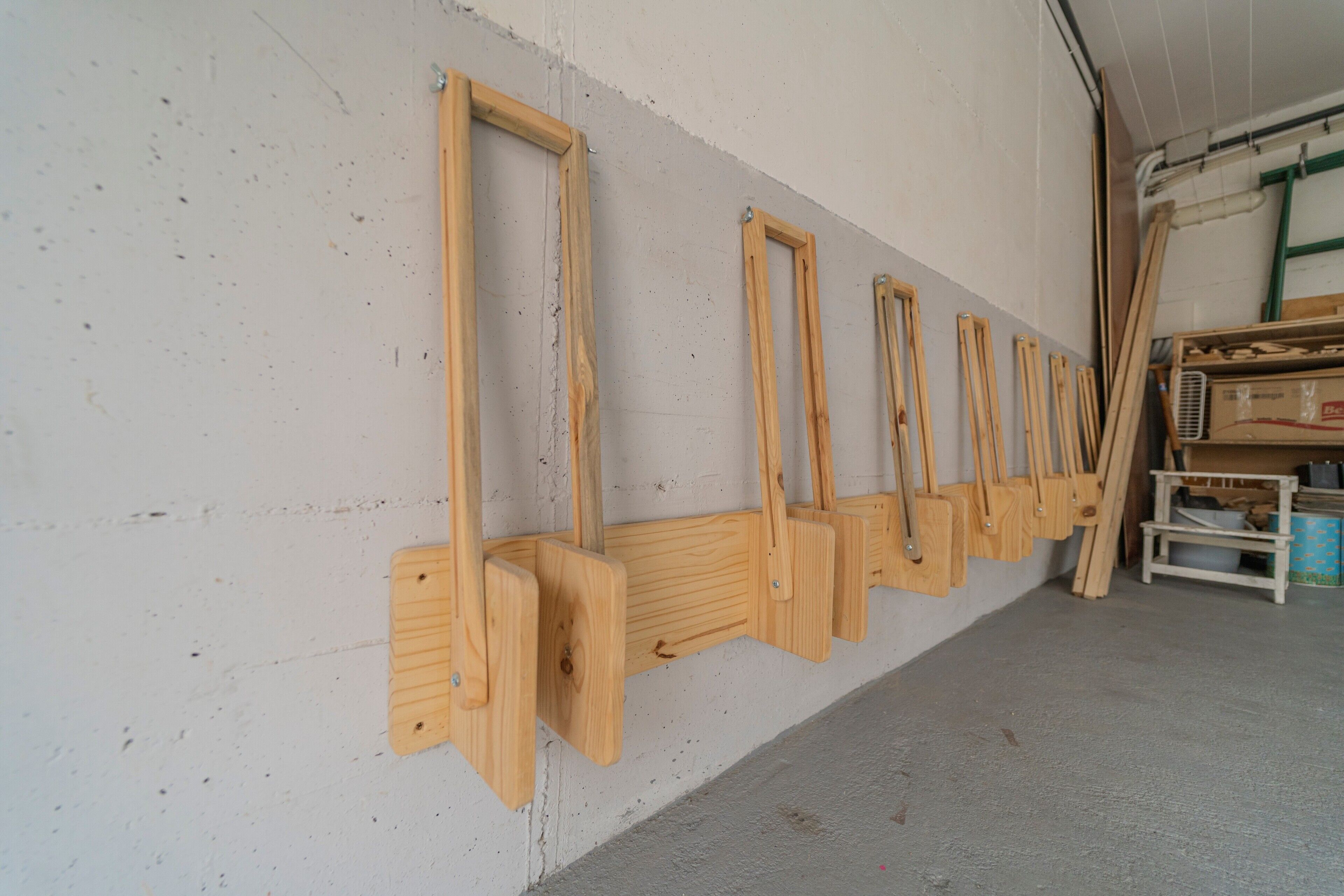 Une rangée d’outils en bois fixée au mur dans un atelier ou un espace de stockage.