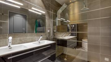 Een moderne badkamer met dubbele wastafels, een grote spiegel en een douche.