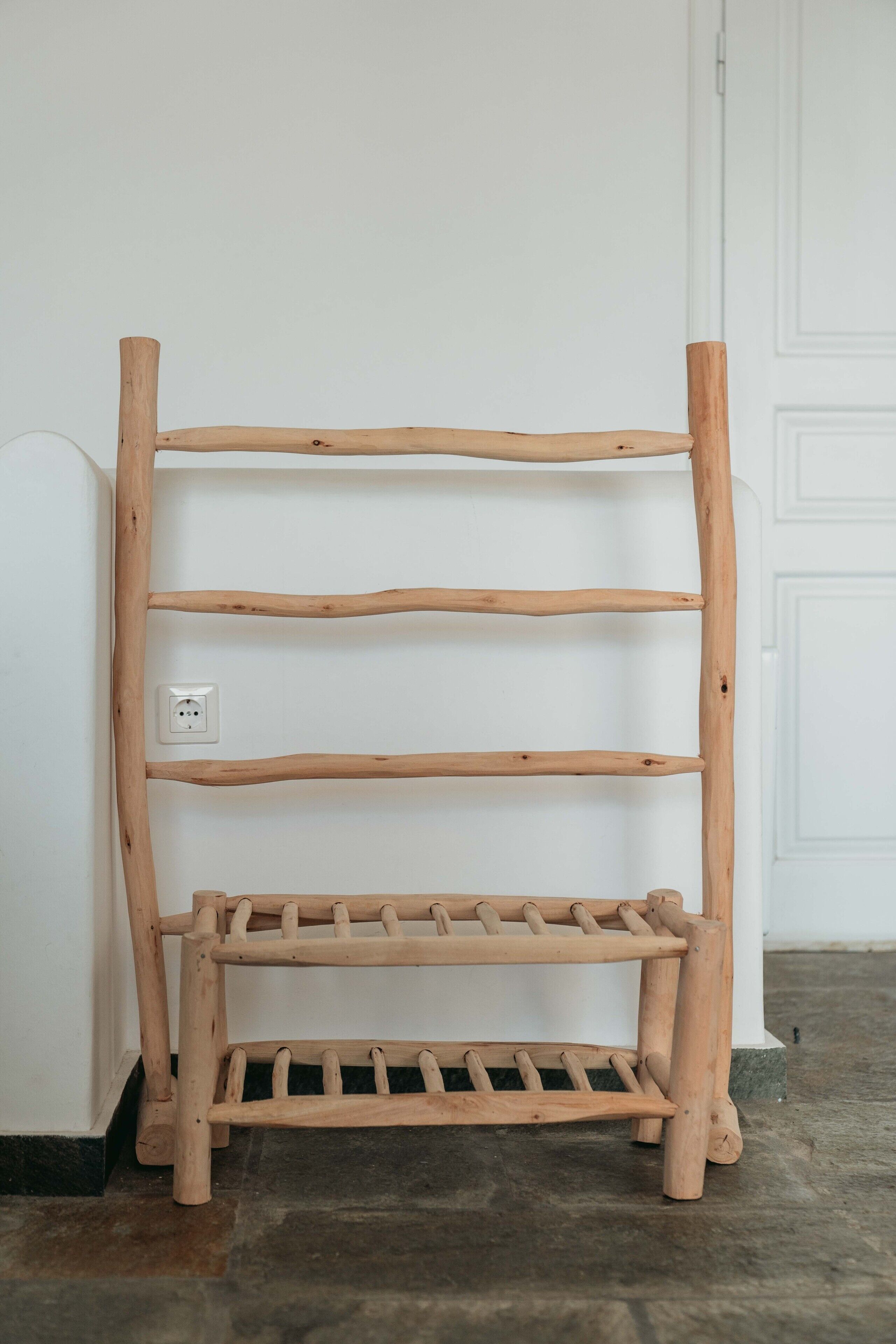 Eine Holzregaleinheit mit vier Regalböden an einer weißen Wand, neben einer Tür mit weißer Fußleiste.