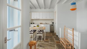 A kitchen with white cabinets, a dining table with chairs, a wooden bench, and a hanging light fixture.