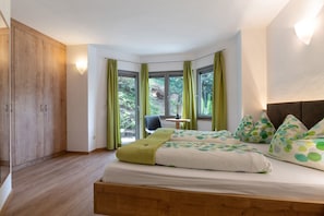 Une chambre à coucher avec un grand lit, une armoire en bois, une petite table et une chaise.