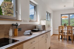 A modern kitchen with a built-in stove, a microwave, and a dining area with wooden chairs and a table.