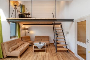 Una habitación estilo loft con sofá, una mesa de centro y una escalera a un entrepiso.