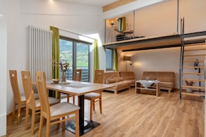 Un interior moderno con zona de comedor, sofá y un espacio tipo loft con escalera.