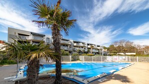 A modern hotel with a swimming pool, palm trees, and a clear blue sky. - Apartment 'Résidence Le Rêve' with Shared Pool, Wi-Fi and Air Conditioning (La Tranche-sur-Mer)