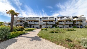 A multi-story hotel with balconies, a gravel pathway, and well-maintained landscaping. - Apartment 'Résidence Le Rêve' with Shared Pool, Wi-Fi and Air Conditioning (La Tranche-sur-Mer)