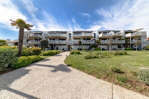 Un hotel de varios pisos con balcones, un camino de grava y jardines bien cuidados.