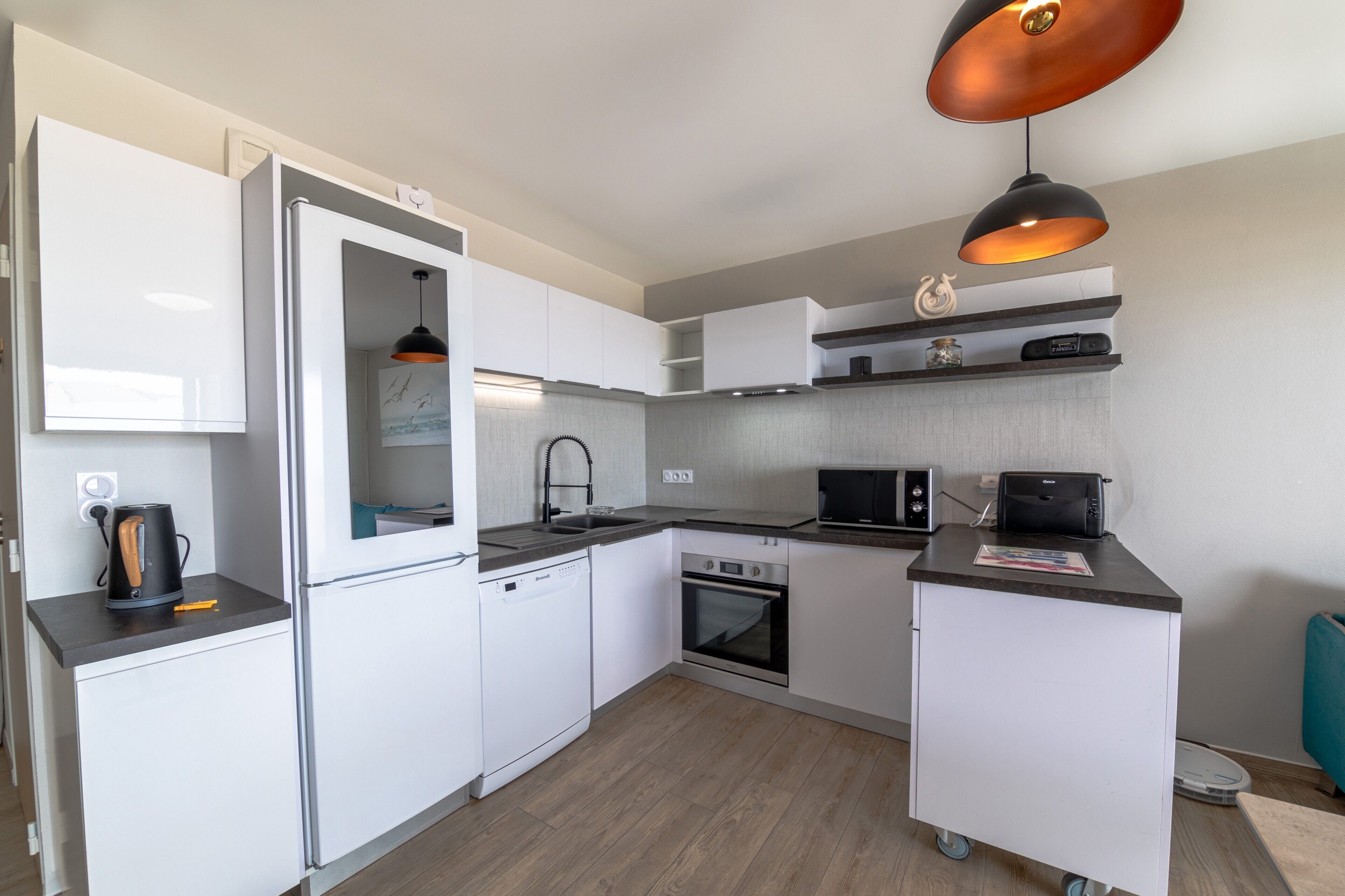 A compact kitchen with a built-in dishwasher, oven, microwave, and a coffee maker on the counter.