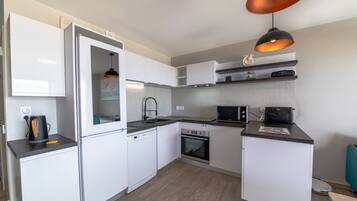 A compact kitchen with a built-in dishwasher, oven, microwave, and a coffee maker on the counter.