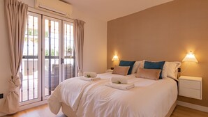 Un dormitorio con una cama, dos lámparas de noche, una mesita de noche, una ventana con cortinas y un equipo de aire acondicionado.
