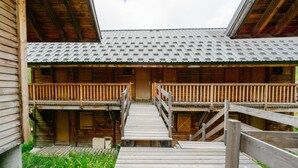 A wooden cabin with a covered porch, a wooden staircase, and a small deck. - Apartment 'Village Gaulois-appt 48r' with Mountain View and Balcony (Saint-François-Longchamp)