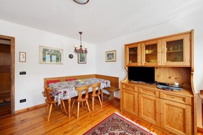A dining area with a wooden table, chairs, a chandelier, and a cabinet with glass doors.
