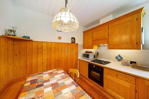 A kitchen with wooden cabinets, a stove, a microwave, and a quilted tablecloth.