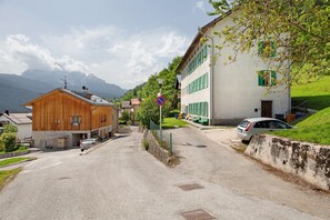 A street with buildings, a no parking sign, and a car parked on the side.