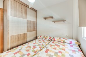 A bedroom with a bed, a wardrobe, and a window.