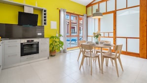 A bright kitchen with a TV, oven, and dining area with chairs and a table.