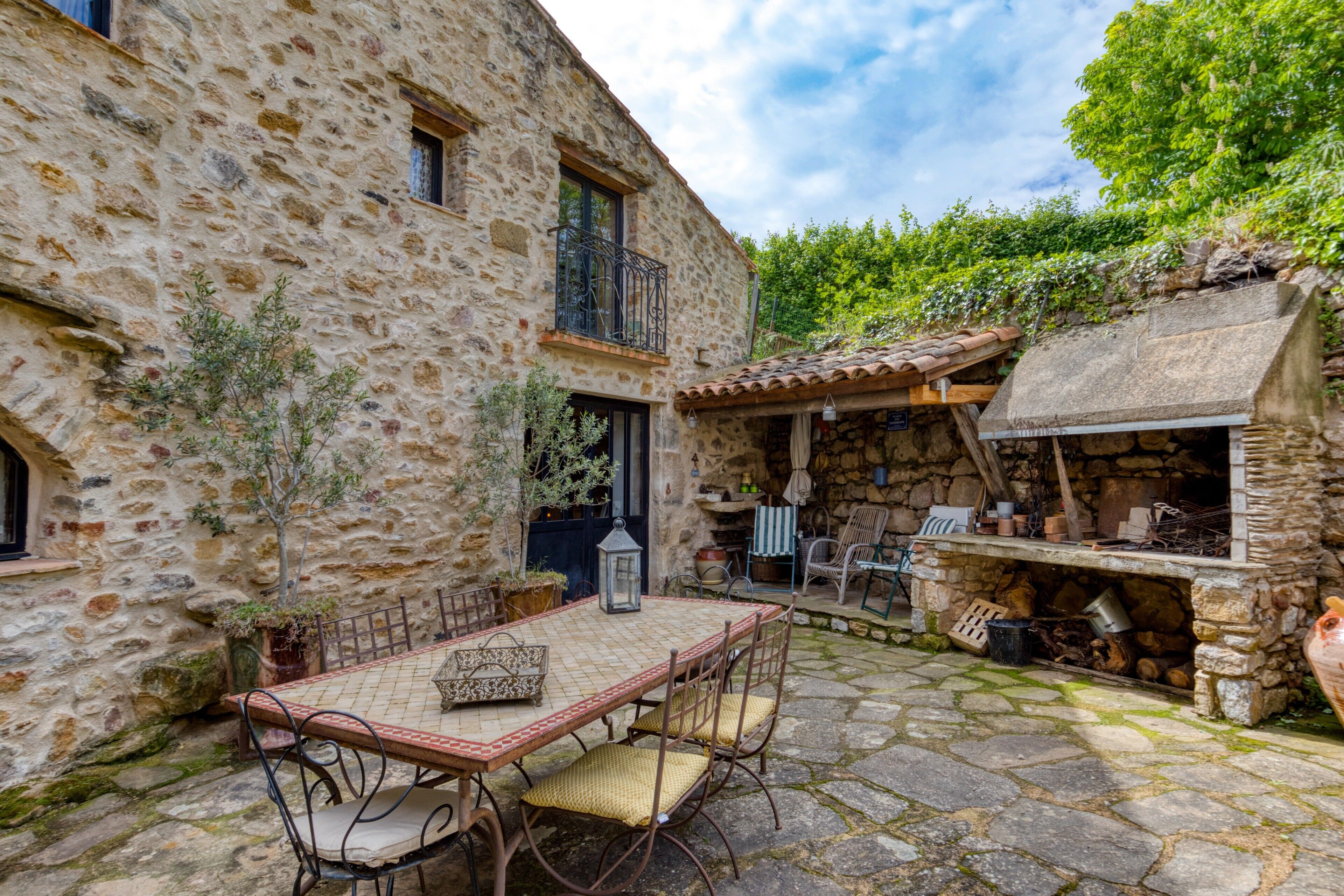 A stone building with a patio, outdoor seating, and a barbecue area.
