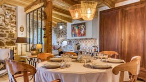 Zona pranzo con tavolo rotondo apparecchiato per sei, circondato da sedie in legno.