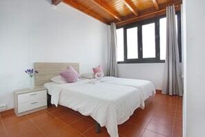 A bedroom with a wooden ceiling, a bed with white bedding, a nightstand with a drawer, and a window with curtains. - Vacation Home 'Lin House' with Private Pool, Private Terrace and Wi-Fi (Corralejo)