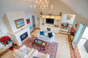 A spacious living area with a fireplace, a large TV, and a chandelier.