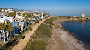 A coastal hotel with a beach view, a fortified tower, and a clear sky.