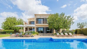 Ein zweistöckiges Haus mit Schwimmbad, Sitzgelegenheit im Freien und einem Garten.