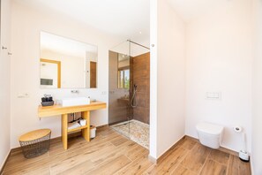 A modern bathroom with a wooden vanity, a large mirror, a glass shower enclosure, and a white toilet. - Villa 'Viduleto' with Mountain View, Private Pool and Wi-Fi (Felanitx)