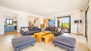 Ein modernes Wohnzimmer mit einer Sofagarnitur, einem Couchtisch und Blick durch eine Glastür.