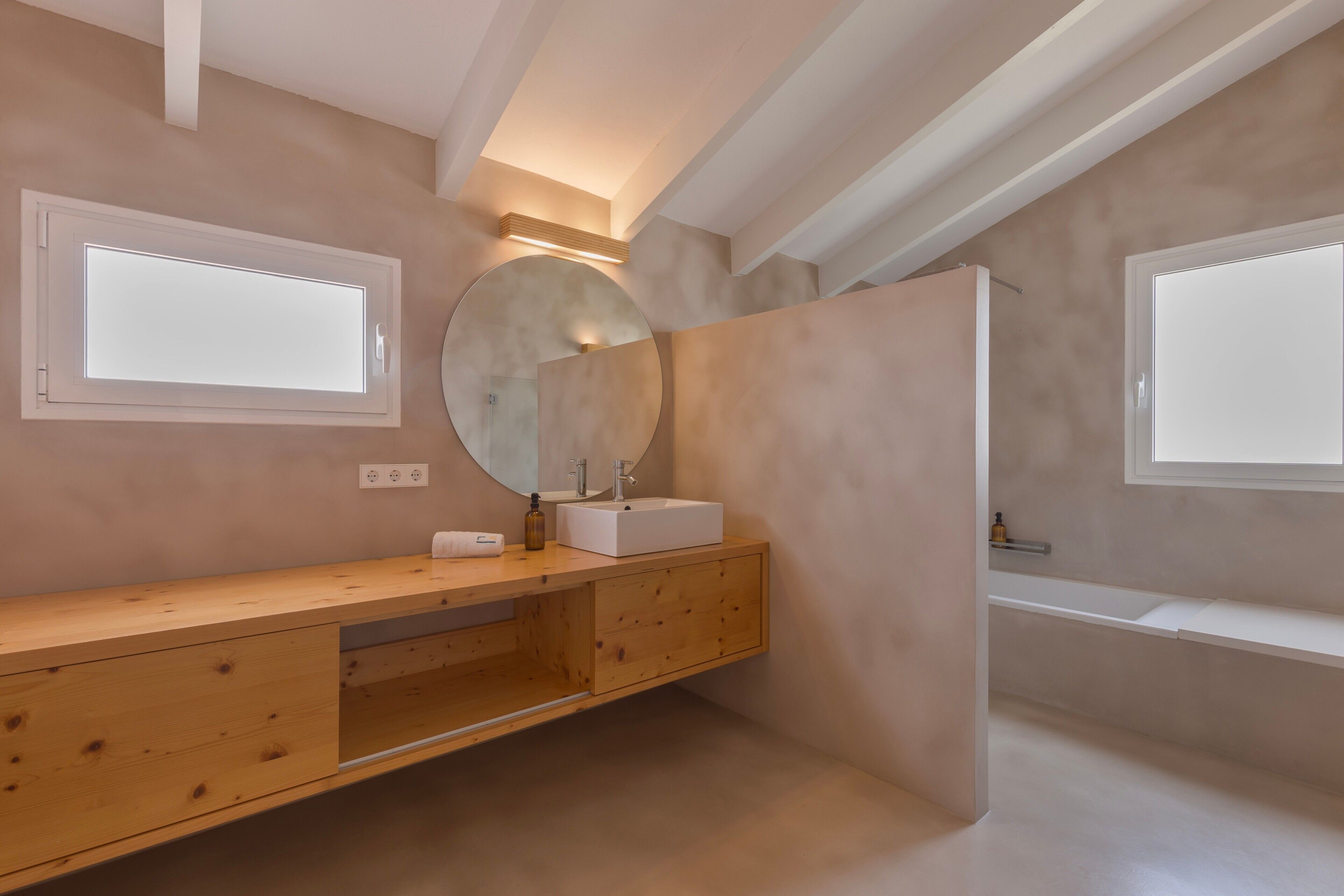 Une salle de bain moderne avec un meuble-lavabo en bois, un grand miroir et une baignoire.