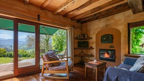 Ein Holzinnenraum mit Schaukelstuhl, Kamin und Blick durch große Glasüren.