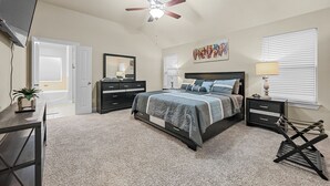 A bedroom with a bed, a desk, a dresser, a ceiling fan, a window with blinds, and a painting on the wall. - Entire Home in Denton, Texas. Centrally Located! Luxurious Home Away from Home! (Denton)