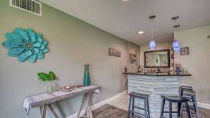 Una cocina con barra, una gran flor decorativa en la pared y un cartel que dice 'Bienvenido a nuestra casa'.