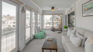Un salon spacieux doté de grandes fenêtres, d’un canapé, d’une table basse et d’un fauteuil suspendu.