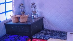 Uma tenda com duas camas, uma mesa e duas lanternas.