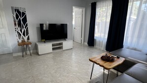 Un salon moderne avec un téléviseur à écran plat, un canapé, une table basse et un panneau décoratif représentant un arbre.