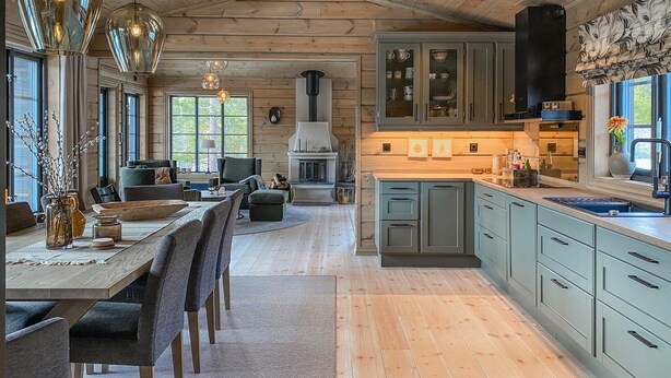 Una cocina amplia con una isla central, piso de madera y una zona de comedor con mesa y sillas.