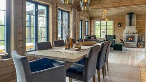 Interior acogedor de una cabaña con comedor, asientos y chimenea.