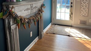 A room with a wooden floor, a door with a decorative wreath, a mirror above a mantelpiece, and a painting on the wall. - Please do not book (Augusta)