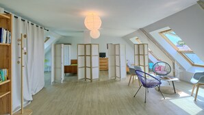 Ein großzügiges Loft mit hohen Decken, Holzboden, einem großen Fenster und einer Deckenleuchte.