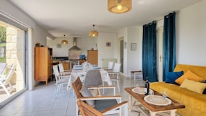 Ein geräumiger Wohnbereich mit Esstisch, Stühlen, einer Couch und einer Küche im Hintergrund.