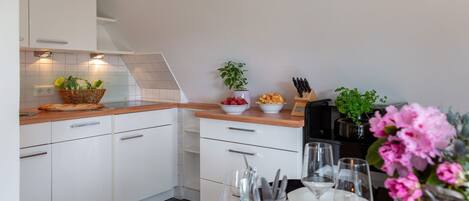 Una cocina moderna con armarios blancos, encimera de madera y zona de comedor lista para una comida.
