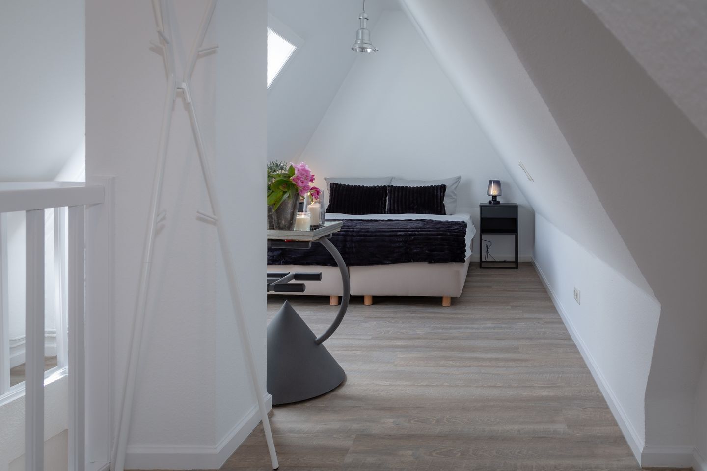 Une chambre à coucher avec un lit, une table de chevet, une lampe et une fenêtre.