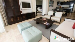 Una sala de estar moderna con un televisor de pantalla plana, un comedor con mesa y sillas, y una cocina al fondo.