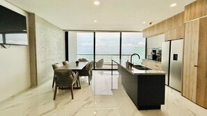 Una cocina moderna con una isla grande, un comedor con vistas y un ventanal que da al océano.